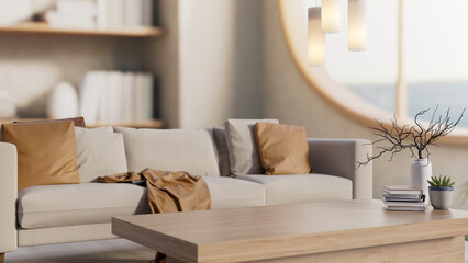 Books and potted plant on wooden table and sofa couch aside round window with lamp in a living room