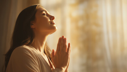 Woman praying with closed eyes and peaceful expression in warm sunlight