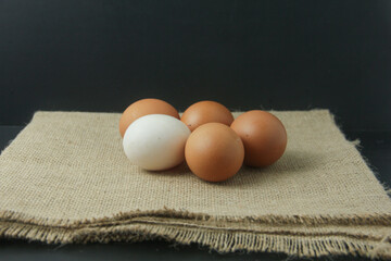 Rustic still-life photograph featuring fresh brown chicken eggs resting on a textured burlap...