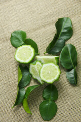Citrus hystrix or kaffir lime or bergamot sliced fruit and its leaves isolated on a brown burlap base