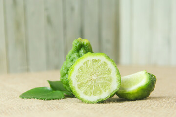 Citrus hystrix or kaffir lime or bergamot sliced fruit and its leaves isolated on a brown burlap base