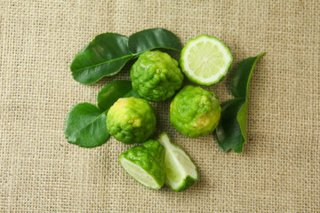 Citrus hystrix or kaffir lime or bergamot sliced fruit and its leaves isolated on a brown burlap base