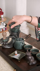 Oriental beverage service. Healthy lifestyle. Table with tea-board woman hand pouring water chinese tea ceremony steam incense for drinking figurine.