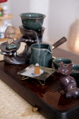 Oriental beverage service. Healthy lifestyle. Table with tea-board pouring water chinese tea ceremony steam incense drinking figurine.
