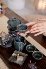Herbal drink. Chinese tea ceremony. Table with tea-board woman hand holding water vapor incense cup figurine.