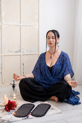 Woman mudra hands. Yoga board. Barefoot sitting in lotus position on sharp nails on mat in front of burning fire candles enjoying sadhu practice spiritual growth mental health.