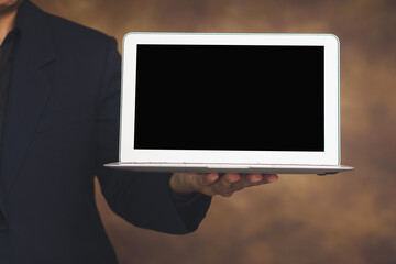 Businessman holding laptop with blank screen for presentation.