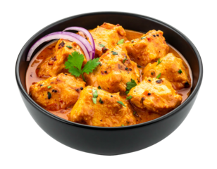 A close-up shot of a flavorful chicken dish in a black bowl. The meal features chunks of chicken coated in a creamy, red-orange sauce. Garnished with red onion and herbs