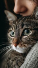 Woman embracing her tabby cat with gentle expression, close-up vertical photo