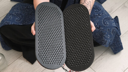 Sadhu board. Yoga tool. Woman sitting in lotus position hand holding sharp nails for practice meditation foot massage spiritual growth.