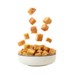 Crispy golden croutons falling into a white bowl.