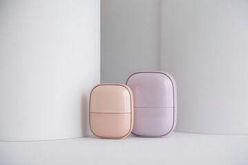 Two cosmetic containers, one pink and one purple, isolated on white background