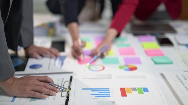 A group of people are working on a project and writing on a white board. There are many different colored sticky notes on the board