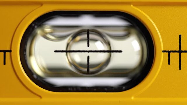 Macro shot yellow spirit level tool with bubble centering between lines. Symbolizes precision accuracy balance in construction work. Ideal for renovation DIY engineering concepts.