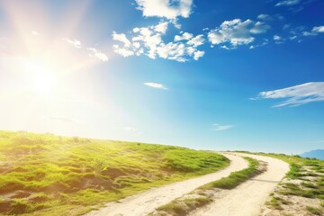 Winding dirt road on a green grassy hill under a bright sunny blue sky with fluffy clouds