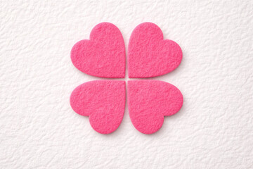 Obraz premium pink felt hearts in a clover design isolated on a textured flat lay background. abstract 3d valentine's day design element.