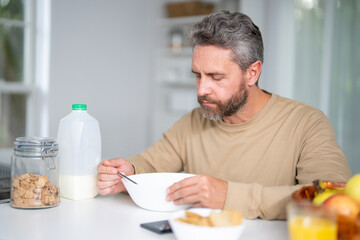 Healthy nutrition mature man. Aged man with healthy products at kitchen. Handsome Senior Man Eating Tasty Meal In Kitchen At Home. Mature Man at Table Enjoying Delicious Food. Morning breakfast.