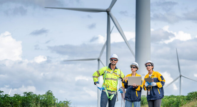 Team of Engineers Planning Project for Renewable Energy Professional Team Inspecting Wind Turbines for Clean Energy Generation Collaboration : Engineers with Blueprint at Wind Farm.