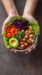 Person Holding a Healthy Buddha Bowl with Roasted Tofu, Avocado, Red Cabbage and Fresh Greens