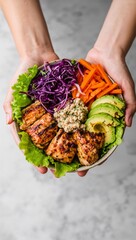 Hands Holding a Nutritious Poke Bowl with Grilled Chicken, Sliced Avocado, Shredded Cabbage and Carrots