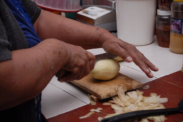 Traditional preparation of Mexican potatoes with chorizo and fresh green salsa using a volcanic stone mortar (molcajete)
