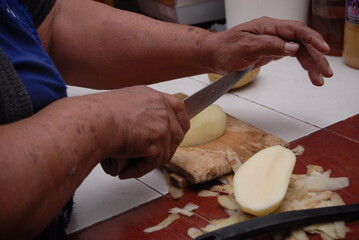 Traditional preparation of Mexican potatoes with chorizo and fresh green salsa using a volcanic stone mortar (molcajete)