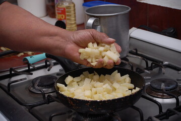 Traditional preparation of Mexican potatoes with chorizo and fresh green salsa using a volcanic stone mortar (molcajete)