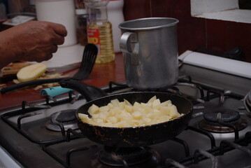 Traditional preparation of Mexican potatoes with chorizo and fresh green salsa using a volcanic stone mortar (molcajete)