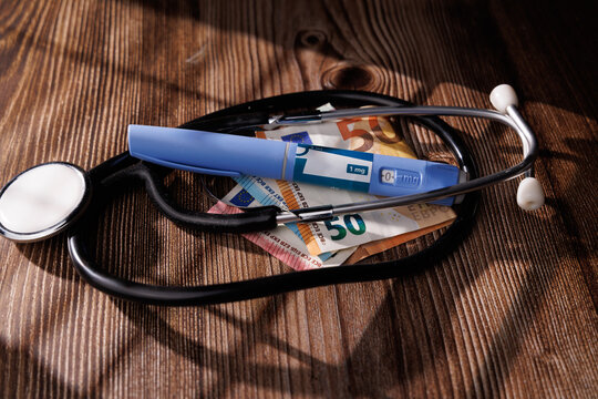 Medical semaglutide pens with a stethoscope and euro bills on a dark wood background for the concept of expensive diabetes health care - Powered by Adobe