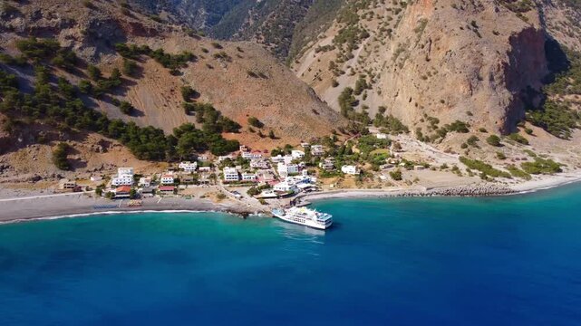 Aerial perspective with downward tilt to reveal Agia Roumeli, a small isolated coastal village which resides at the end of the Samaria Gorge hike - Southern Crete, Greece