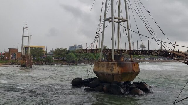 Shot of the old Paravi Duwa bridge ruins in Matara, Sri Lanka, highlighting its weathered concrete base and rusted metal under a stormy, overcast monsoon sky