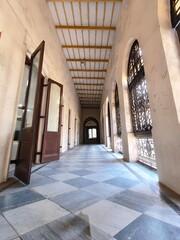 Long Hallway with Checkered Floor and Arched Windows