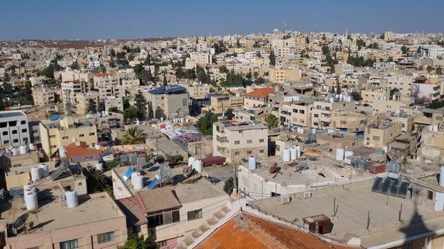 Panoramic view over Madaba, Jordan, famed for its ancient mosaics, showing rooftops and streets stretching to the horizon on a sunny day under a clear blue sky