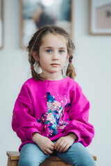 Portr&auml;t eines nachdenklichen kleinen M&auml;dchens mit Z&ouml;pfen in einem pinken Pailletten-Sweatshirt