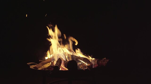 Static shot of a crackling campfire with glowing embers and bright yellow flames against the deep black of a rural night in the Cerrado natural reserve in Goi&aacute;s, Brazil