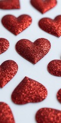 Fototapeta premium Red glitter hearts scattered on white surface, festive and romantic.