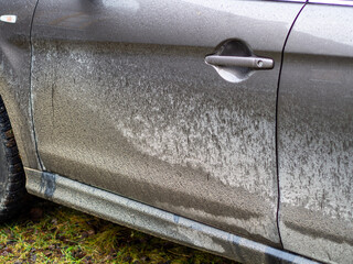 A car covered in mud. Autumn, winter and spring mud on the roads. Car wash services. Side view of a very dirty car
