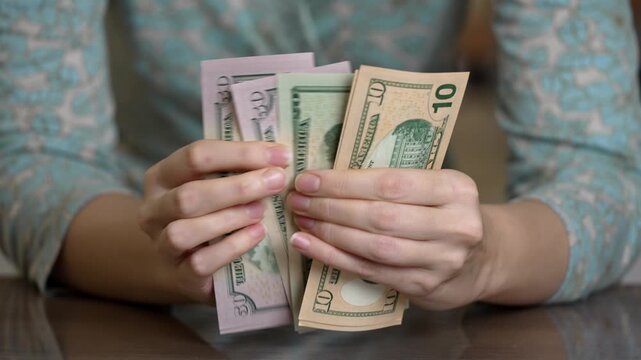 female hands fanning stacked bills at table, tight closeup of sorting tens and twenties, quick but careful