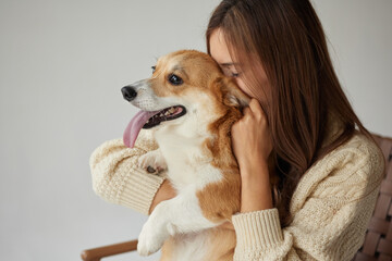 Woman nuzzling corgi dog indoors affectionate pet owner bonding moment