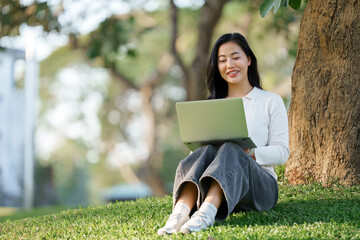 Young woman remotely working on laptop in park