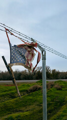 A tattered American flag remains snagged on a weathered barbed-wire fence