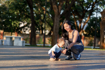 Mother teaching toddler playing outdoors in park