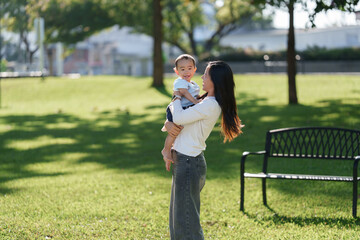 Loving mother holding happy baby boy in park