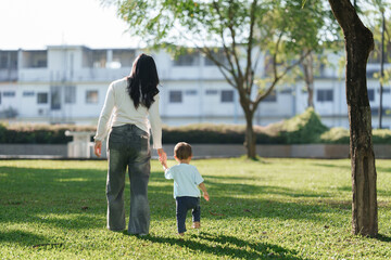 Mother and child walking hand in hand in park