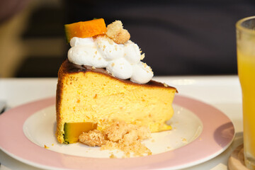 Pumpkin cheesecake slice with whipped cream, candied pumpkin, and crumbs on a pink plate