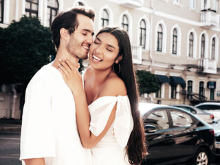 Fototapeta premium Smiling beautiful woman and her handsome boyfriend. Happy cheerful family. Sexy couple posing in the street at sunrise. During romantic date at sunny summer day outdoors. Looking at each other