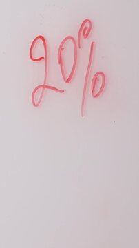 A white marker writes percentages in red ink on a plain white surface. The writing is clean and clear, emphasizing the discount or sale event being promoted.