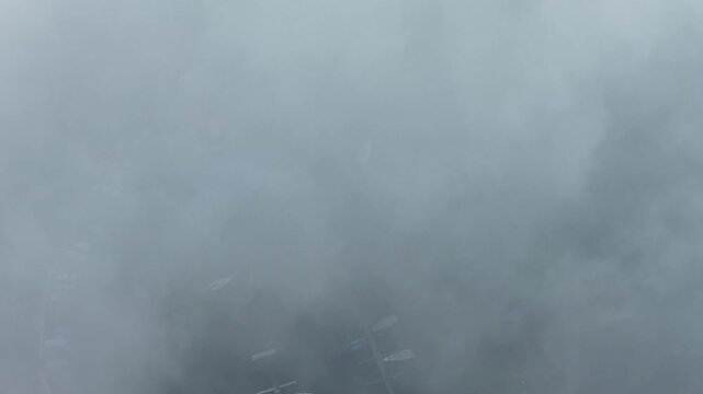 Aerial top-down view of marina boats emerging through dense fog, creating abstract nautical atmosphere and mystery.