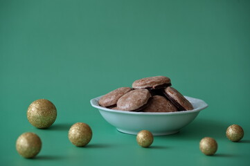 Christmas cookies in a bowl and Christmas balls against green background