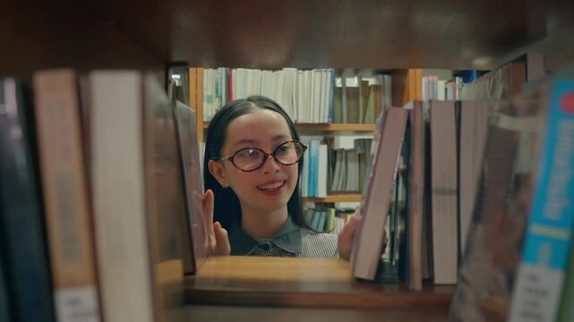 Asian young girl reader searching for books to read in quiet library. 